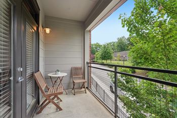A patio with a table and chairs overlooking a road.